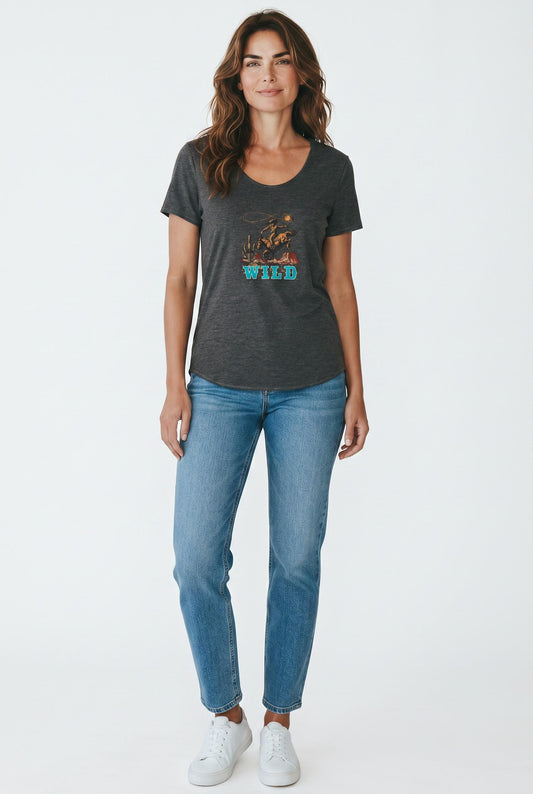 A woman modeling a dark charcoal gray t-shirt with a colorful graphic print on the front, paired with blue jeans and white sneakers, against a plain white studio background.