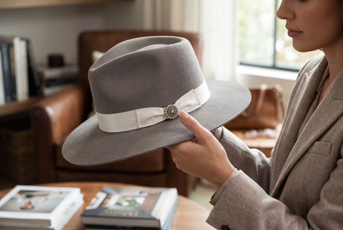 Spirit Warrior Provisions Sofia beige felt hat with white ribbon and sunflower concho held by a woman in a blazer