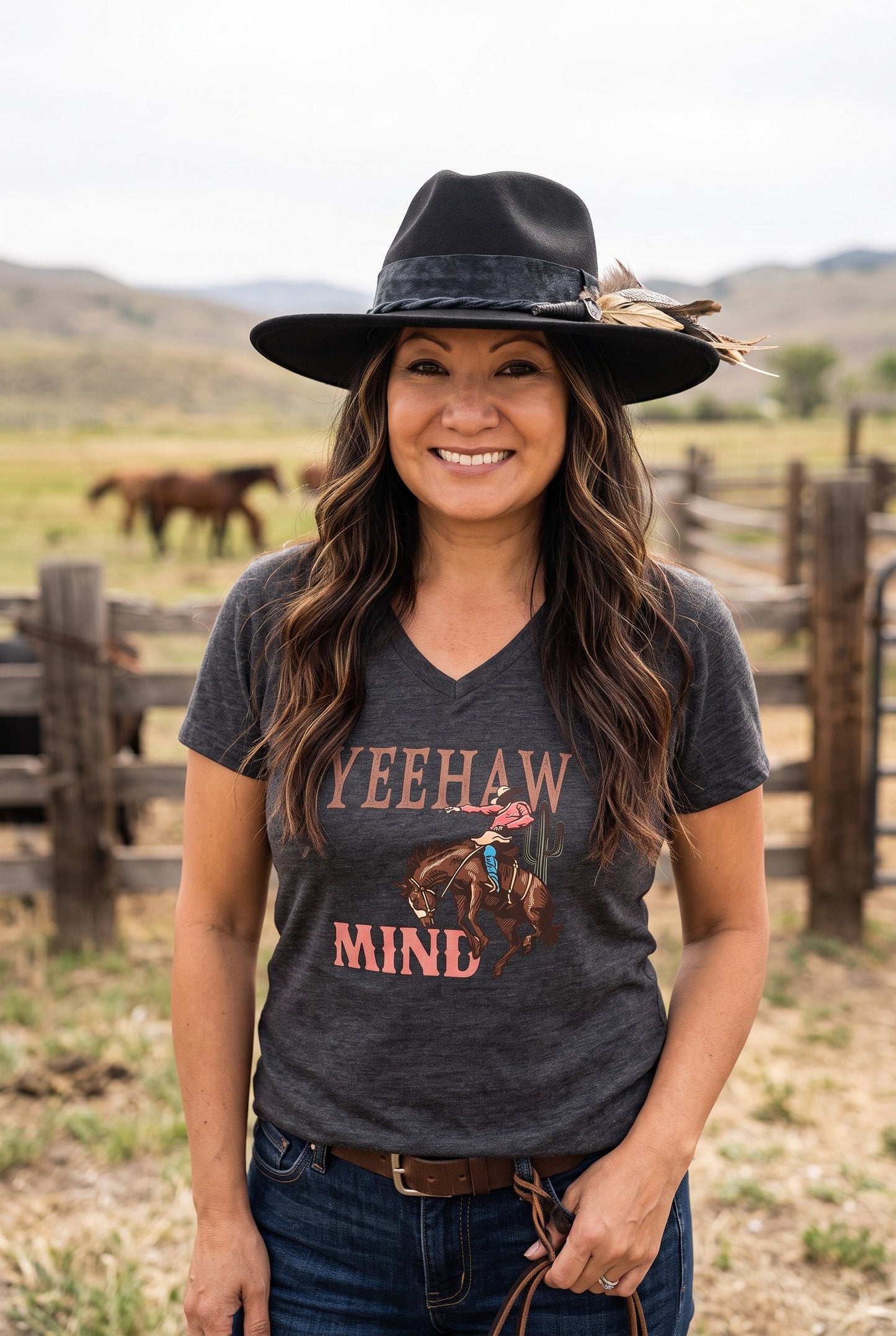 Woman wearing a Spirit Warrior Provisions black felt pinch front hat with feather detail on a ranch with horses