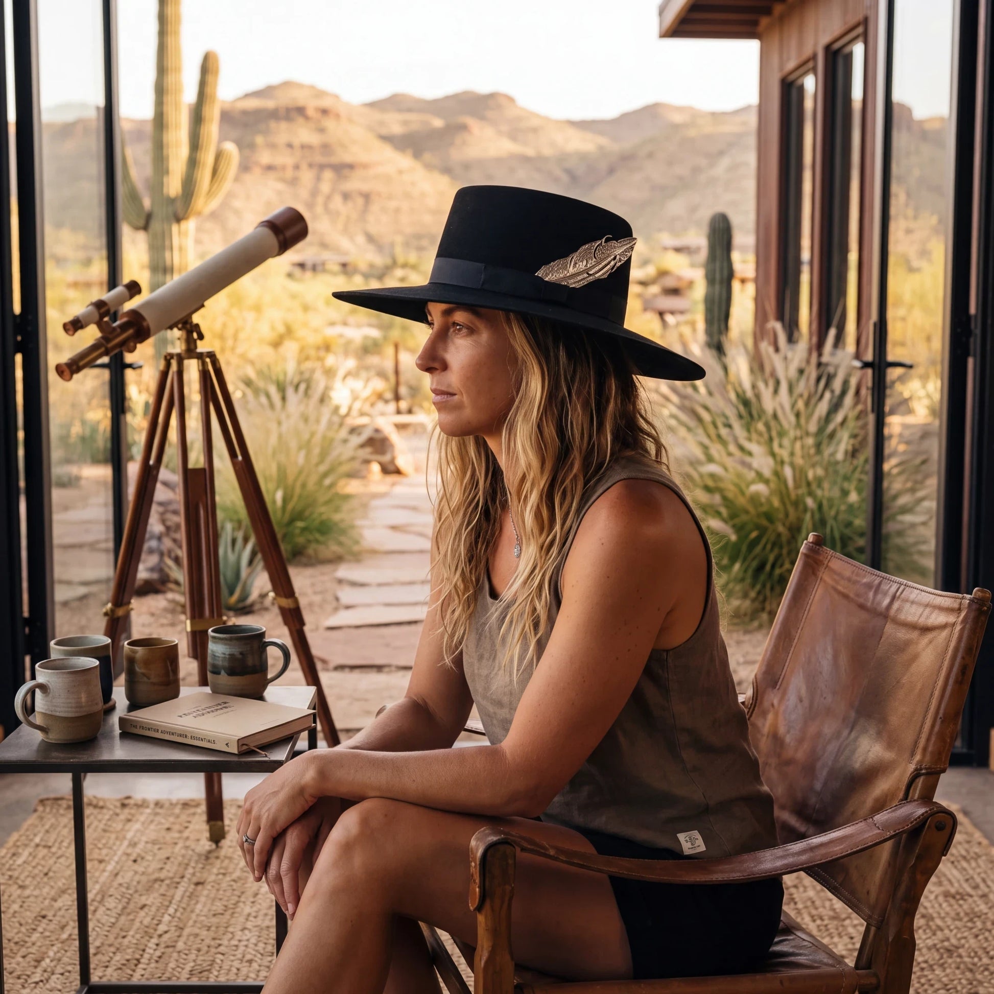 Spirit Warrior Provisions black gambler felt hat with silver pheasant tail detail worn by a woman in a desert setting.