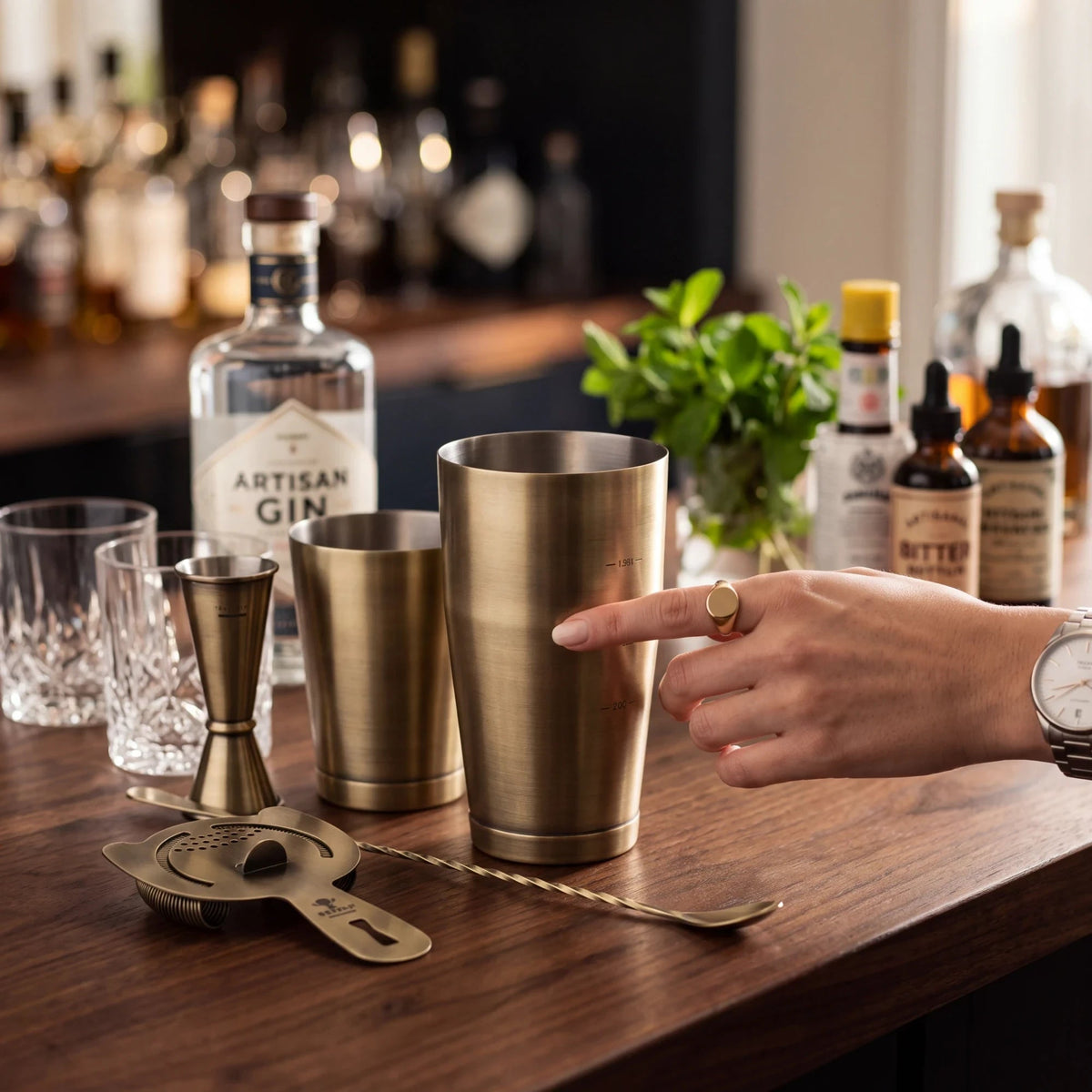 Spirit Warrior Provisions professional brass cocktail shaker set with jigger, strainer, and spoon on a wooden bar