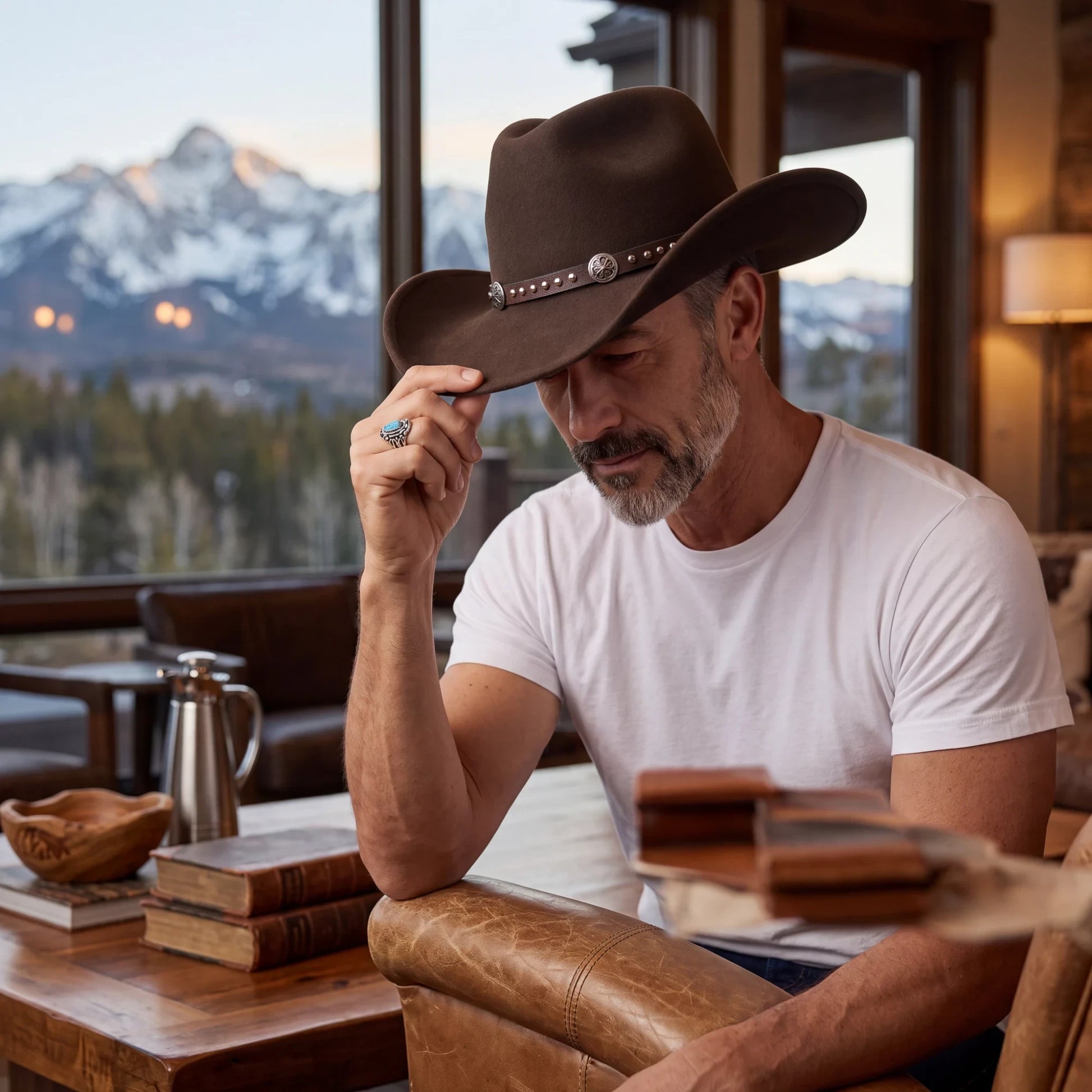 Spirit Warrior Provisions dark brown wool cowboy hat with silver concho leather band worn by a man in a rustic room.