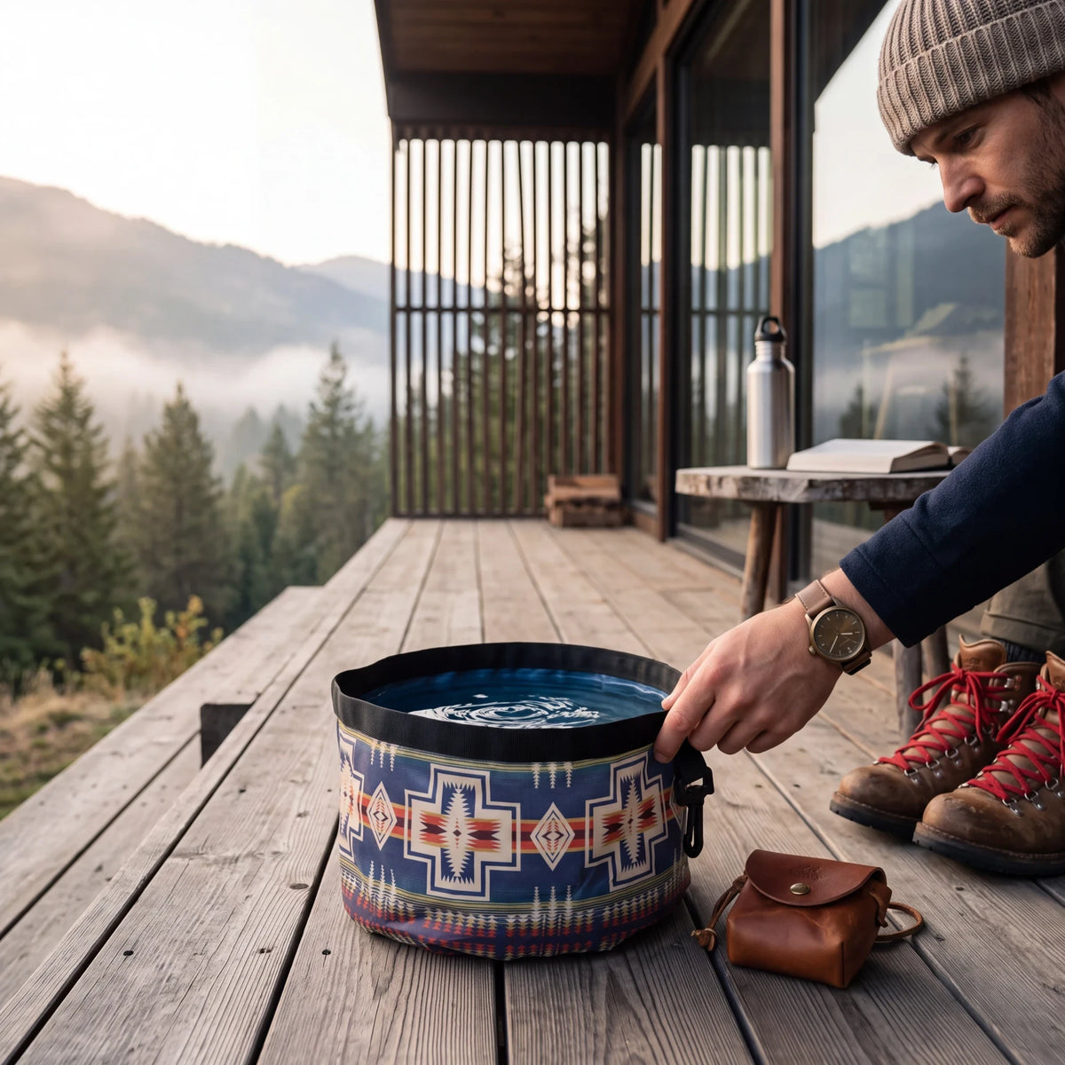 Spirit Warrior Provisions collapsible polyester dog bowl with a blue geometric pattern on a wooden deck at sunrise.