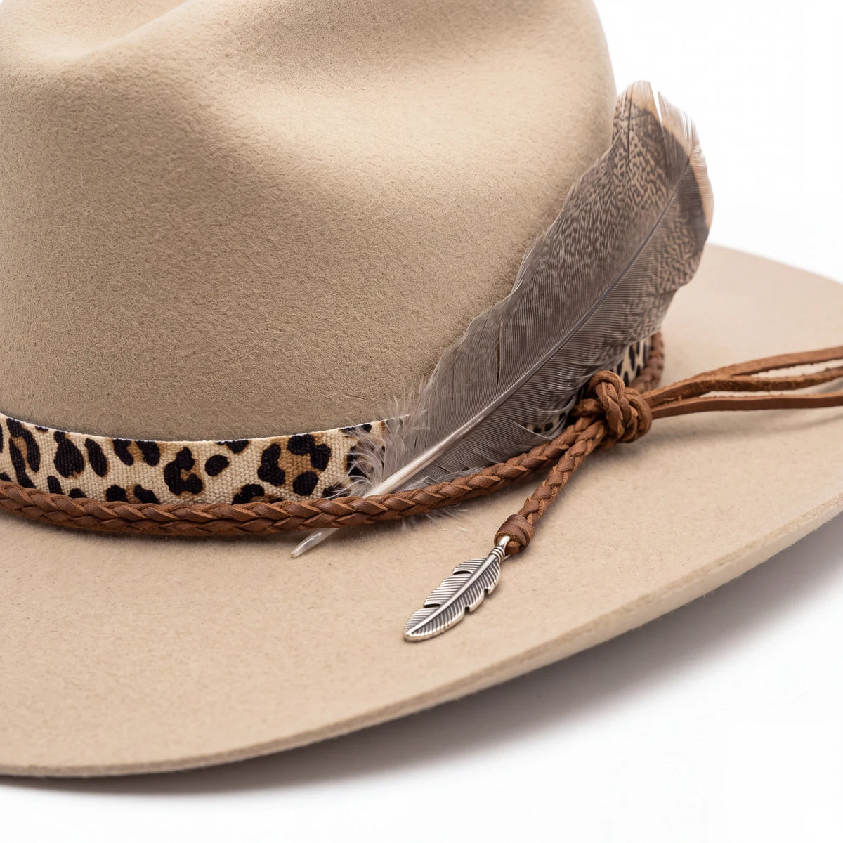Spirit Warrior Provisions sand 6X felt cattleman hat with cheetah leather band, braided fawn trim, and feather detail.