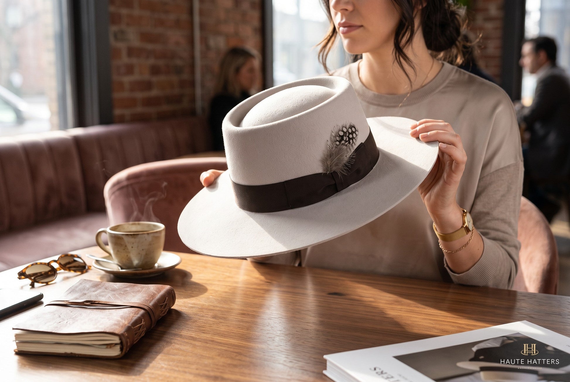 Spirit Warrior Provisions sand gambler hat with flat brim, grosgrain ribbon, and feather detail held by a woman.